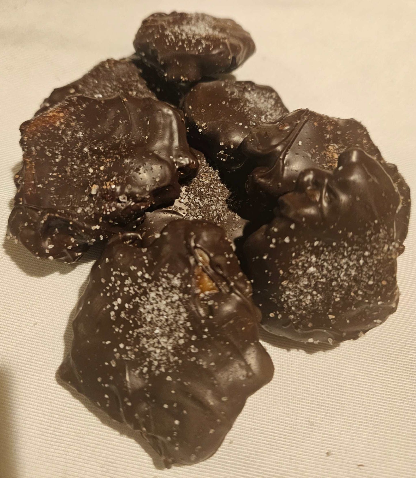 Hand-dipped caramel pecan clusters with sea salt on smooth chocolate in a white box